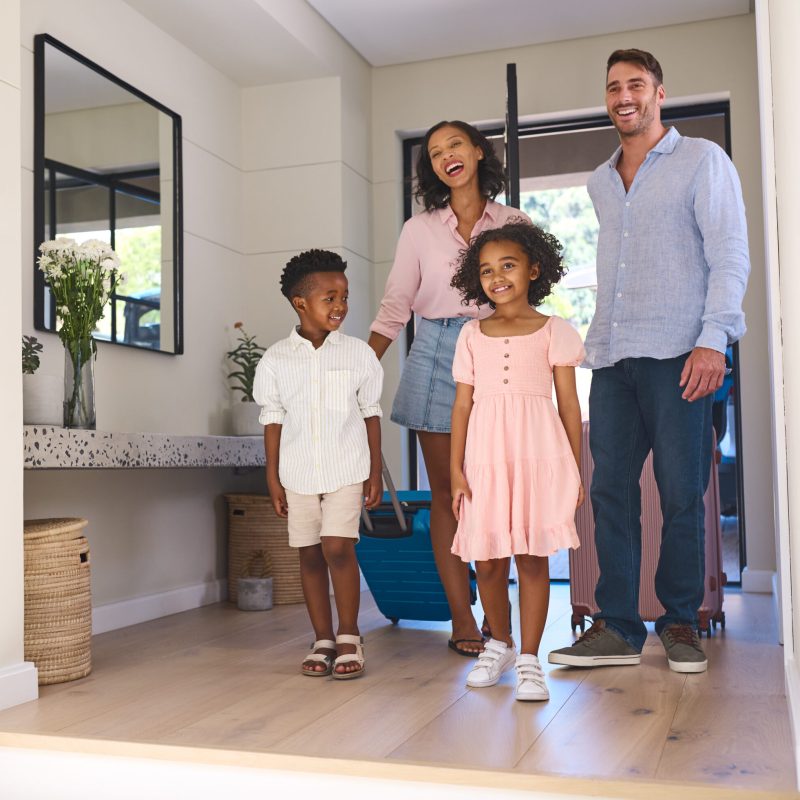 Excited Multi Racial Family With Luggage Arriving In House Or Apartment For Summer Vacation